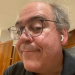 Bijan Parsia - Boian has grey hair is wearing glasses an EarPod in his ear.nd has an