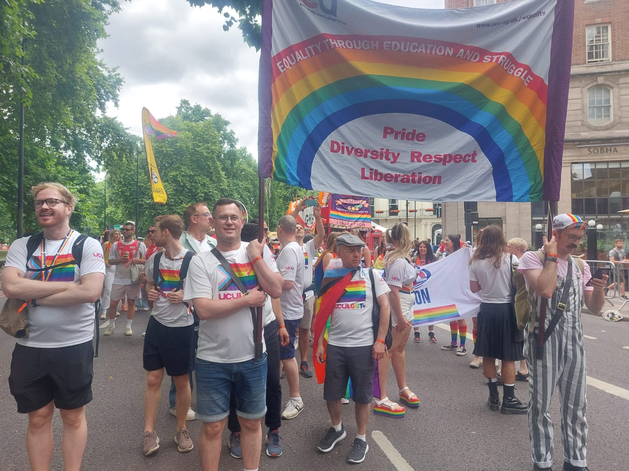 Mark carrying a banner in a Pride parade
