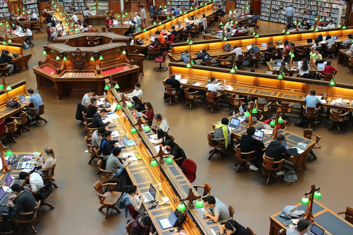 People working in an elaborate library reading room