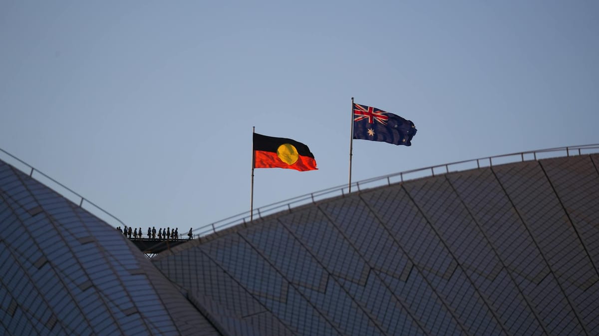 The Australian national flag flying beside the Aboriginal Flag of Australia on a rooftop. 