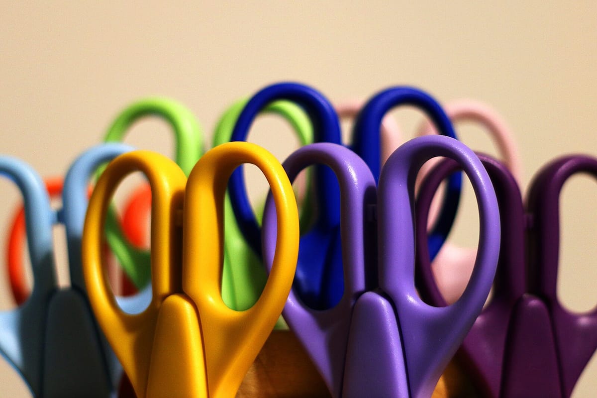 Pairs of scissors with handles in various colours including yellow, purple, blue and green. 